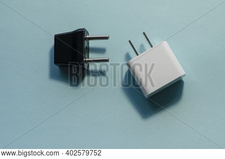 Black And White Interchangeable Dc And Ac Plugs. Wall Adapters For Usa And Europe On Blue Background