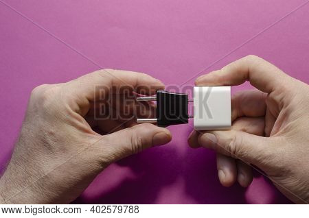 Ac And Dc Adapters In Men's Hands. The Male Connects The Black Wall Adapter For Europe And The White
