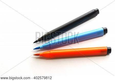 Three New Multi-colored Felt-tip Pen On A White Background. Black, Orange And Blue  Felt-tip Pens Fo