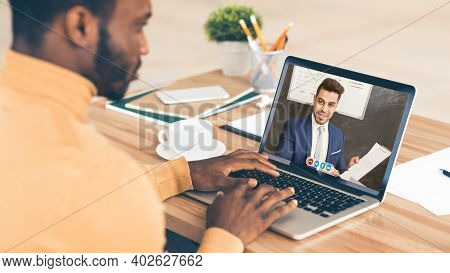 Black Businessman Consulting With Business Coach Via Video Call Sitting At Laptop Computer In Modern