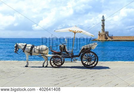 Horse Drawn Carriages On The Quayside With The Venetian Lighthouse At The Harbour Entrance To The Re