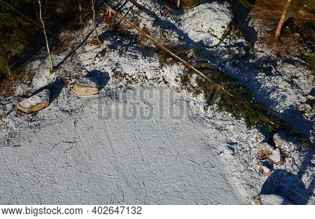 Snowy Parking From Above. Large Stones Delimit The Parking Space. A Barrier Made Of Giant Tribes Tha