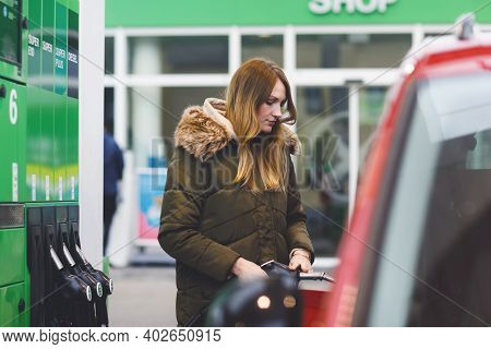 Young Caucasian Woman At Self-service Gas Station, Hold Fuel Nozzle And Refuel The Car With Petrol, 