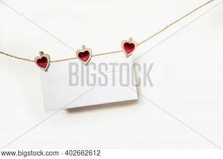 Blank Envelope Hanging On A Rope With Clothespins In The Shape Of Hearts On A White Background On Va