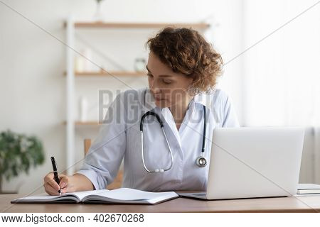 Concentered Young Female General Practitioner Involved In Paperwork.