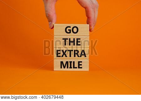 Go The Extra Mile Symbol. Wooden Blocks With Words 'go The Extra Mile'. Male Hand. Beautiful Orange 