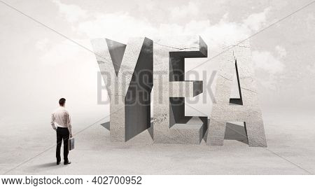 Rear view of a businessman standing in front of YEA abbreviation, attention making concept