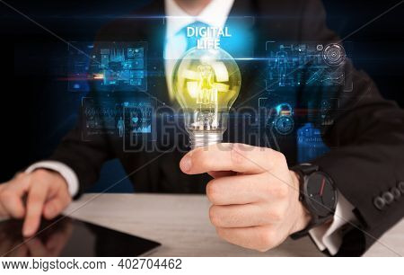 Businessman holding lightbulb with DIGITAL LIFE inscription, online security idea concept