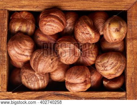 Hazelnuts in wooden box on brown wood background. Top view. Filbert. Cobnut. Healthy food. Vegetarian nutrition