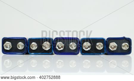 Five Blue Used Pp3 Batteries Lined Up On A White Background With Reflection. Main Battery For Person