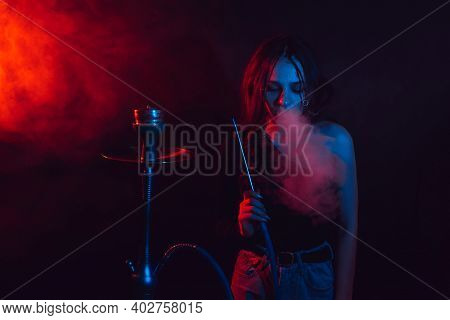 Model Girl Smokes Hookah, Sheesha. The Girl Exhales With Pleasure. Color Light