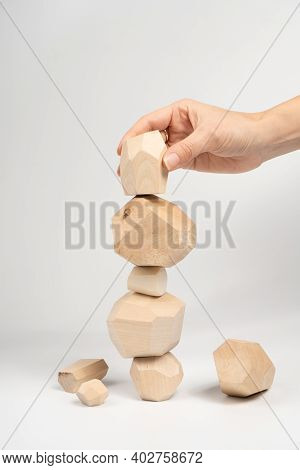 Tumi-ishi Puzzle Game. A Woman Or A Girl Places Her Hand On Another Block Of Wood On Top Of An Unsta