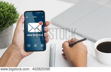 Newslettering Concept. Woman Got New Message On Smartphone While Working In Office, Holding Cellphon