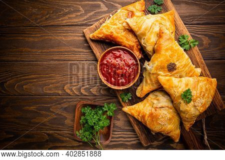 Samsa Or Samosas With Meat And Vegetables With Tomato Sauce On Wooden Background. Traditional Asian 