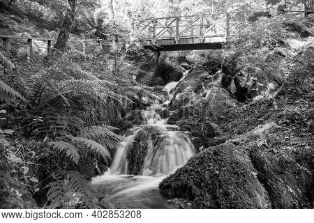 Long Exposure Of A Waterfall Flowing Under A Bridge At Canonteign Falls In Dartmoor