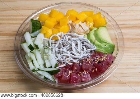 Poke With Mango, Tuna, Avocado, Gula And Cucumber On A Transparent Bowl