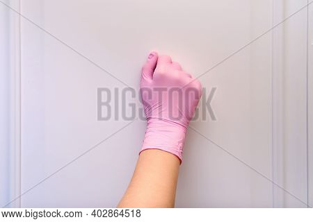 A Woman Hand In Protective Medical Gloves Knocks On The Door Of A House, Close-up