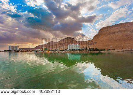 Legendary Dead Sea. The smooth surface of the very salty sea water reflects the sky and clouds. Low winter clouds are reflected in the green sea water. Israel