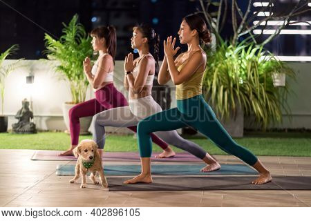 Group of asian women in sportswear pants practicing yoga during city lockdown in their apratment with distance in background of cityscape illumination night. Work out fitness healthy lifestyle concept