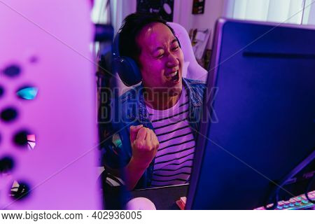 Young Asian Male Gamer Won And Victory The Winning Game With Headset And Pc Computer. Overjoyed Live