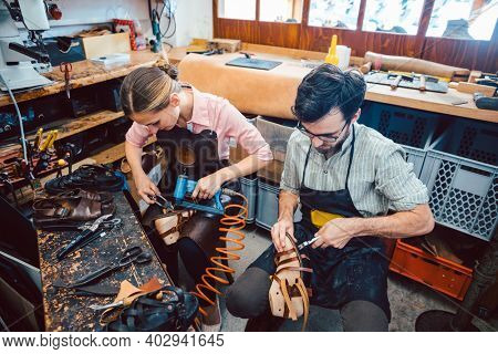 Woman and man shoemaker working together in the workshop
