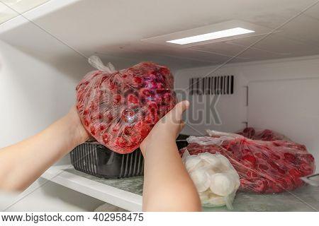 The Woman Takes Out A Bag Of Frozen Cherries From The Freezer.