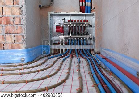 Underfloor Heating System. Manifold With Pipes In Building