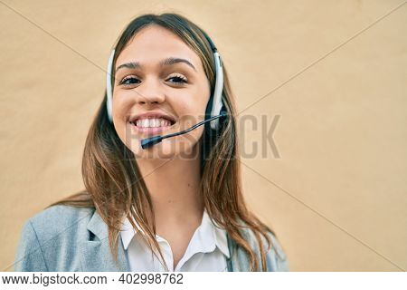 Young latin call center aget girl smiling happy using headset at the city.