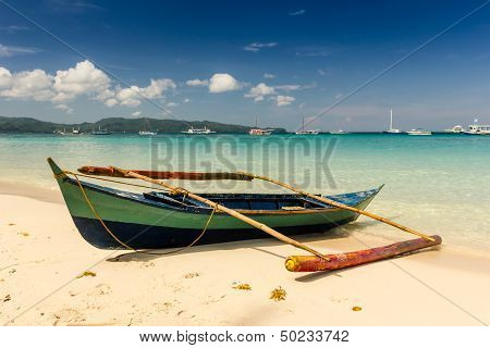 A Small Outrigger Style Banca Boat Rests On A Tropical Beach