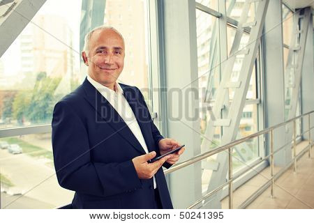 serious businessman holding tablet pc and looking at camera