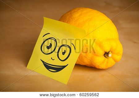 Drawn smiley face on a post-it note sticked on a lemon