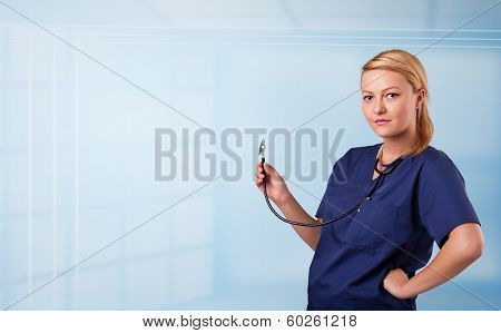Pretty young nurse in hospital listening to empty copy space with sthetoscope