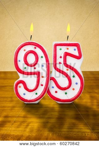 Burning birthday candles number 95 on a wooden background