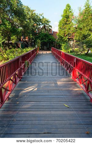 Wooden bridge with red fence in green park