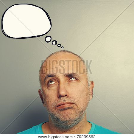 portrait of bored senior man looking up at speech bubble over grey background