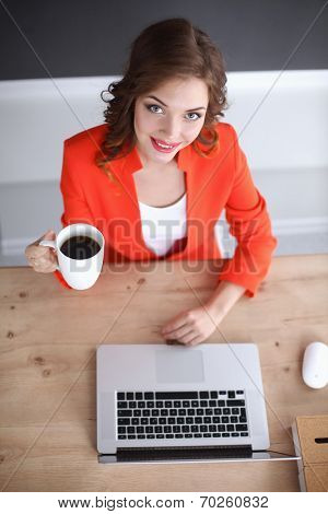 Attractive woman sitting at desk in office, working with laptop