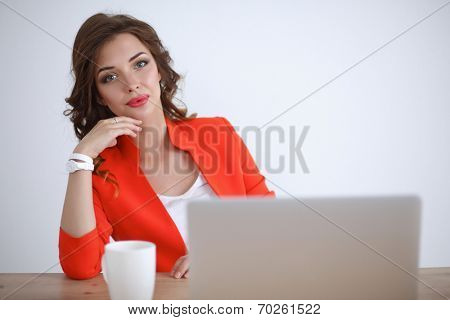 Attractive woman sitting at desk in office, working with laptop