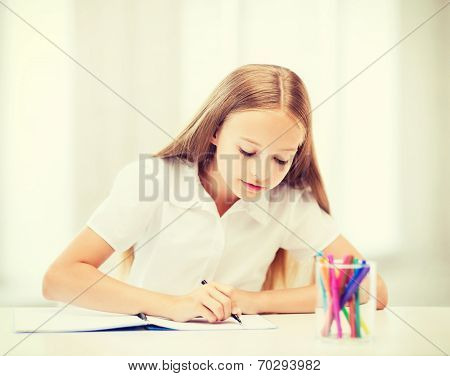 education and school concept - little student girl drawing at school