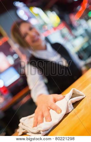 Pretty barmaid wiping down bar in a bar
