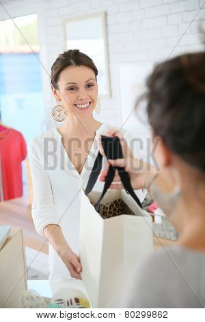 Seller in clothing store giving bag to customer