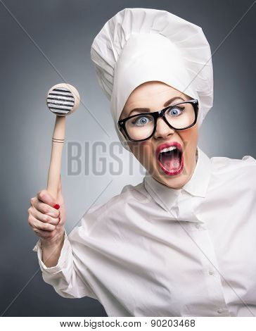 Mad Woman Cook With A Hammer Punching You, Isolated On Gray. Humorous Concept