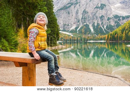 Blonde Young Girl Sitting On Picnic Table At Lake Bries