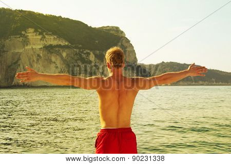 Sportive man on the sea with outstretched arms - pure liberty.