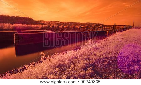 Infrared Lock and Dam on a River. Sun Flair. Orange Colorization.