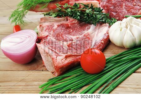 fresh raw meat : fresh red beef ribs with thyme , red chili pepper , cherry tomato , and garlic on wooden board