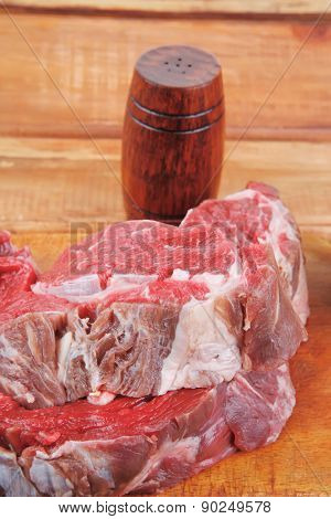 fresh raw uncooked beef fillet mignon entrecote on board prepared for cooking on wood table wtih cutlery and castors