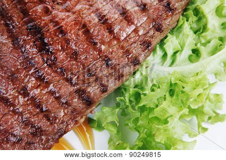meat food : roast steak boneless with roast onion, served on green lettuce salad on dish isolated over white background
