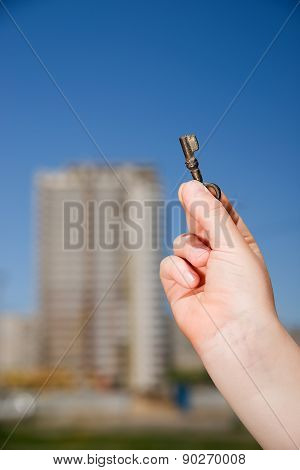 Child Hand Holding An Old Key To The House Against The Sky
