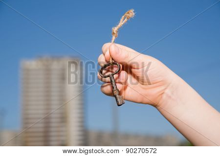 Child Hand Holding An Old Key To The House Against The Sky