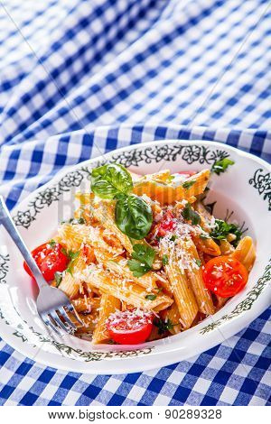Plate with pasta pene Bolognese sauce cherry tomatoes parsley top and basil leaves